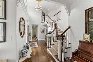 Entrance foyer featuring a high ceiling, ornamental molding, a notable chandelier, and dark hardwood / wood-style flooring