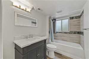 Full bathroom featuring LVP flooring, a textured ceiling, vanity, toilet, and shower / tub combo