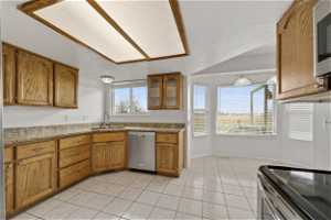 Kitchen featuring sink, stainless steel appliances, light tile floors, and a wealth of natural light