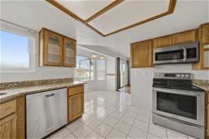 Kitchen featuring a textured ceiling, stainless steel appliances, light granite counters, and light tile floors
