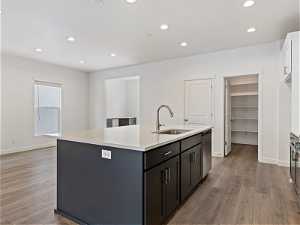 Kitchen featuring sink, light hardwood / wood-style flooring, white cabinetry, and a kitchen island with sink