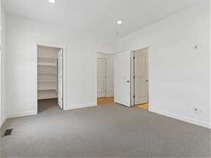 Unfurnished bedroom with light colored carpet, a walk in closet, and a closet