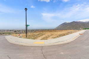 View of street with sidewalks, street lights, a mountain view, and curbs