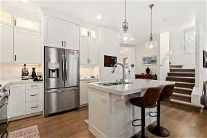 Kitchen with sink, stainless steel fridge, hardwood / wood-style flooring, and white cabinets