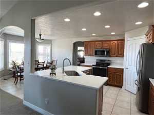 Kitchen featuring sink, pendant lighting, a kitchen island with sink, backsplash, and stainless steel appliances
