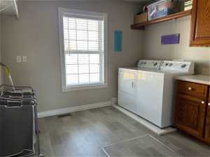 Laundry area with cabinets, washing machine and dryer, and dark hardwood / wood-style floors