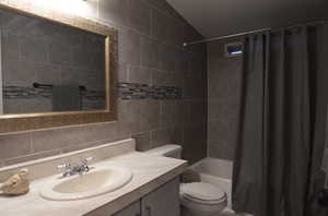 Full bathroom with vanity, toilet, shower / tub combo, and tile walls