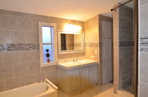 Master bathroom with tile floors, a textured ceiling, tile walls, and large vanity