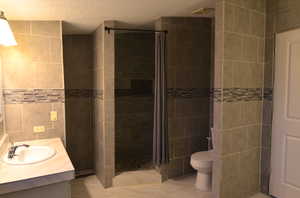 Master bathroom with a tile shower, tub, tile floors, tile walls, and vanity