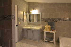 Master bathroom featuring a textured ceiling, tile walls, vanity, separate bathtub and shower, and tile flooring