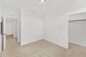 Unfurnished bedroom featuring light carpet and a closet