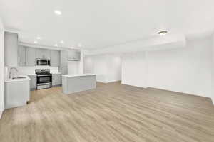 Kitchen with light hardwood / wood-style flooring, stainless steel appliances, sink, and gray cabinets