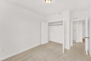 Unfurnished bedroom with light carpet and a closet