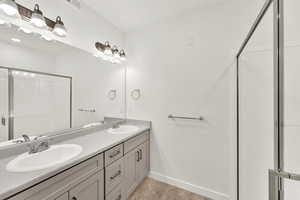 Bathroom featuring an enclosed shower, oversized vanity, tile floors, and dual sinks