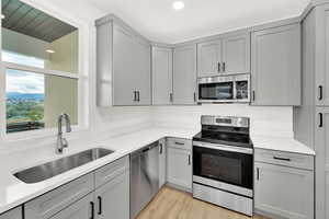 Kitchen featuring appliances with stainless steel finishes, sink, gray cabinetry, and light hardwood / wood-style flooring