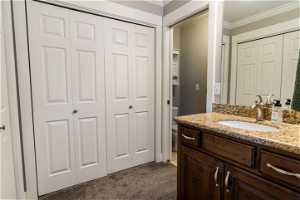 Bathroom featuring toilet, large vanity, and crown molding