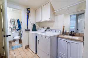Clothes washing area featuring separate washer and dryer, sink, cabinets, and hookup for a washing machine