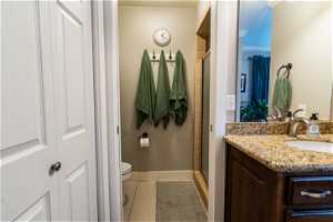 Master suite with vanity, a shower with door, toilet, tile floors, and crown molding