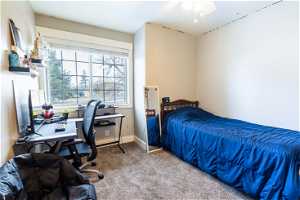 One of two bedrooms on the second floor with carpet flooring and ceiling fan