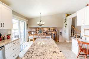 Kitchen featuring white cabinets, a chandelier, decorative light fixtures, light tile floors, and dishwasher