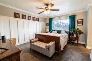 Master bedroom featuring dark colored carpet, ornamental molding, and ceiling fan
