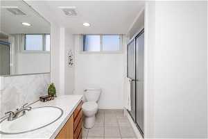 Bathroom with tile floor, shower, toilet, and large double vanity