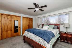 Main bedroom featuring multiple closets, light carpet, and ceiling fan