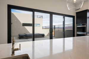 Interior space featuring sink, stainless steel double oven, and light stone countertops