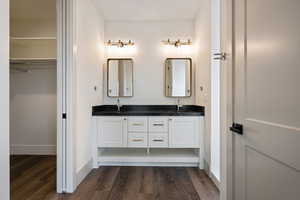 Bathroom featuring dual sinks, large vanity, and wood-type flooring