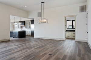 Unfurnished living room featuring a chandelier, a towering ceiling, sink, and dark hardwood / wood-style floors