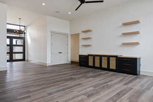 Unfurnished living room with ceiling fan with notable chandelier and dark hardwood / wood-style flooring