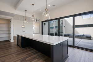 Kitchen featuring sink, dark hardwood / wood-style flooring, pendant lighting, and a kitchen island with sink