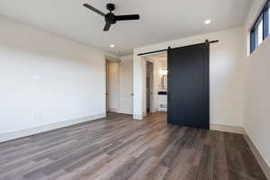 Spare room with ceiling fan, dark hardwood / wood-style floors, and a barn door