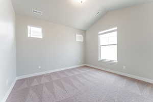 Carpeted empty room with lofted ceiling