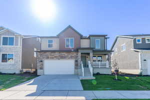 View of front of house featuring a garage, covered porch, and a front yard