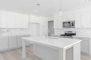 Kitchen featuring a kitchen island with sink, backsplash, and stainless steel appliances