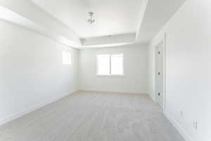 Unfurnished room with carpet floors and a tray ceiling