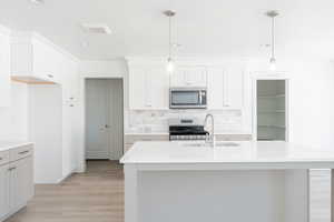 Kitchen with white cabinetry, tasteful backsplash, appliances with stainless steel finishes, and light wood-type flooring