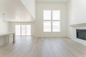 Unfurnished living room featuring a notable chandelier, a fireplace, and light wood-type flooring