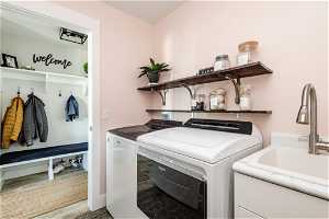 Clothes washing area with washer and dryer, sink, and hardwood / wood-style floors