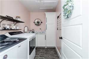 Clothes washing area featuring cabinets, independent washer and dryer, and dark tile floors
