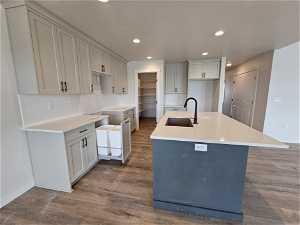 Kitchen with sink, a center island with sink, backsplash, and hardwood / wood-style flooring