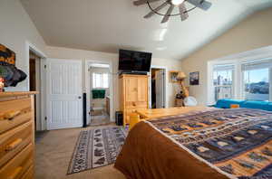 Bedroom featuring lofted ceiling, light colored carpet, ensuite bath, and ceiling fan