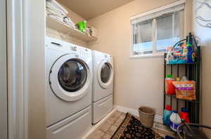 Clothes washing area featuring light tile floors and washer and dryer