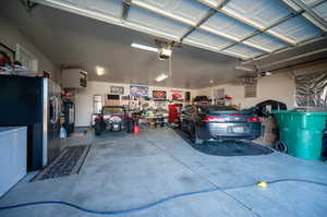 Garage featuring stainless steel fridge with ice dispenser, a garage door opener, a workshop area, and fridge