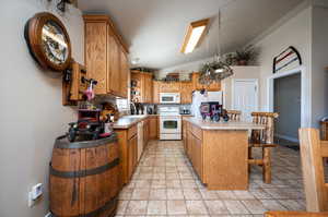 Kitchen featuring light tile floors, white appliances, lofted ceiling, and sink