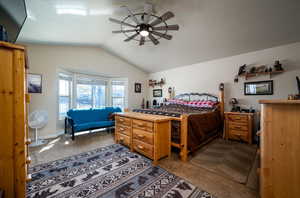 Carpeted bedroom featuring lofted ceiling and ceiling fan