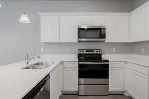 Kitchen featuring hardwood / wood-style floors, sink, stainless steel appliances, and white cabinets