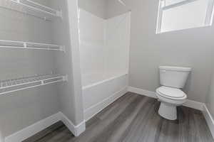 Bathroom featuring toilet, tub / shower combination, and wood-type flooring