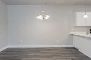 Unfurnished dining area featuring sink, a notable chandelier, and dark wood-type flooring